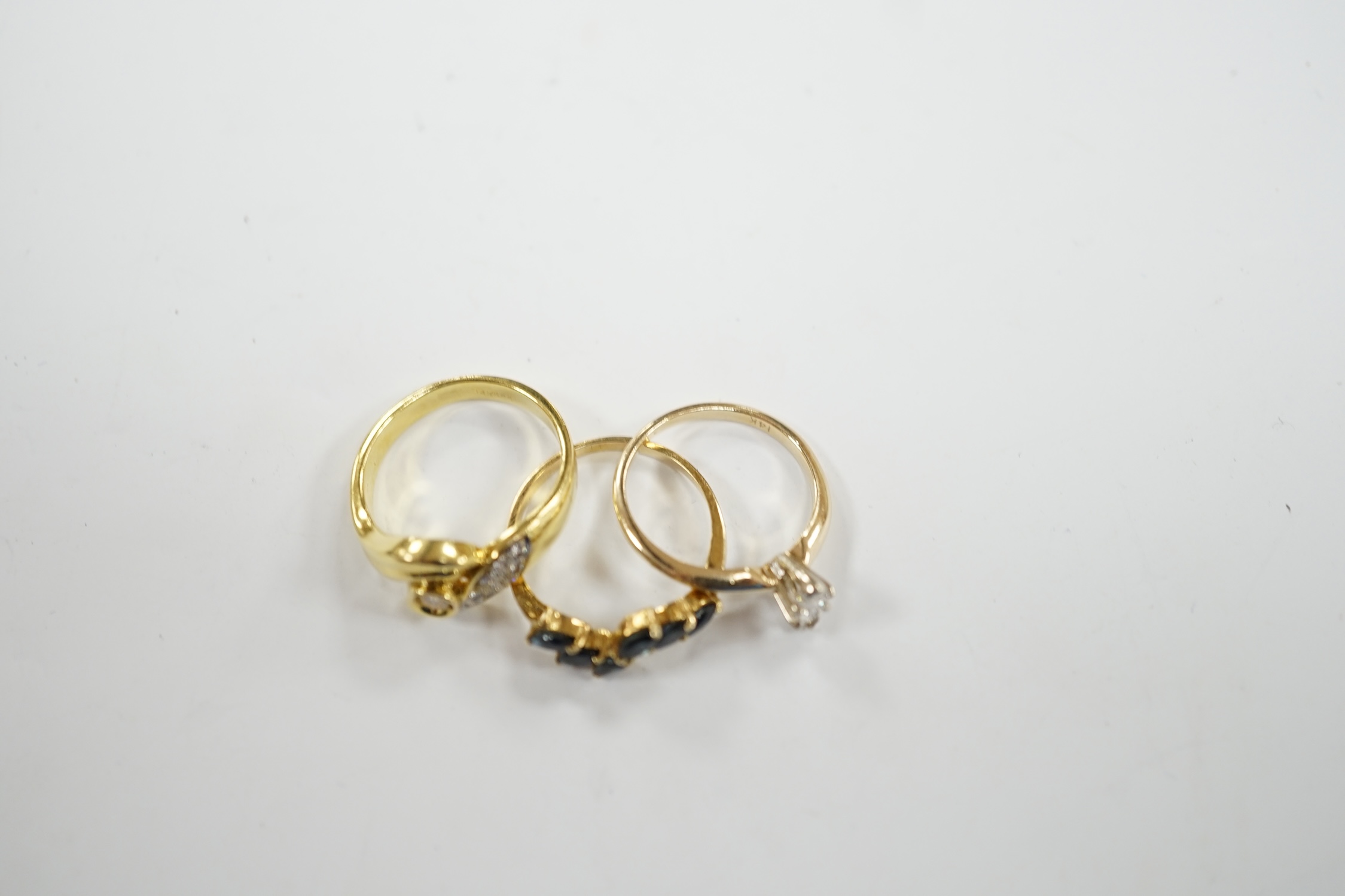 Three assorted modern 14k and gem set rings, including single stone marquise cut diamond, diamond chip set and sapphire set, gross weight 7.7 grams.